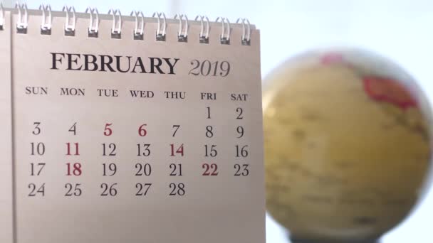 Movimiento de febrero 2019 calendario con globo de tierra borrosa girando fondo
 - Metraje, vídeo