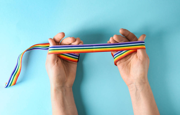 Mujer sosteniendo cinta de arco iris como símbolo de LGBT en el fondo de color
 - Foto, imagen