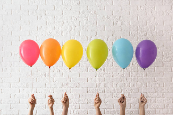 Γυναίκες κατέχουν ουράνιο τόξο αέρα μπαλόνια σε ανοιχτόχρωμο φόντο. ΛΟΑΤ έννοια - Φωτογραφία, εικόνα