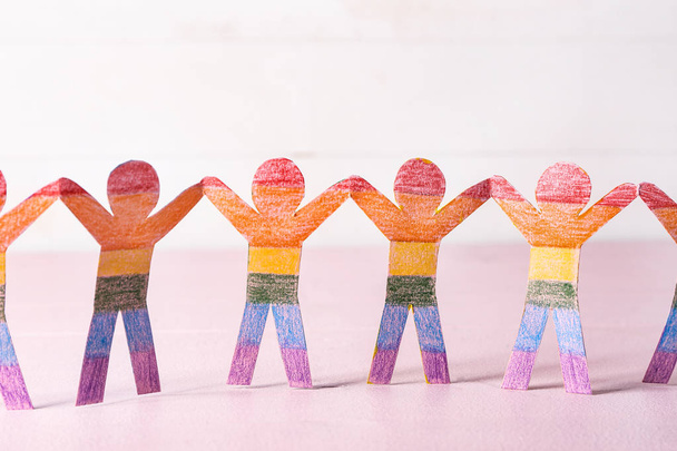 Figuras humanas de papel arco iris en mesa de color. Concepto LGBT
 - Foto, imagen