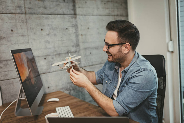 Young entrepreneur having fun and showing little model of airplane in office - Photo, image