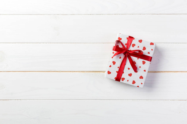 Valentin vagy más holiday kézzel jelen van papír, piros szívek és ajándék doboz a holiday wrapper. Jelen doboz ajándék a fehér fa asztallap Kilátás-val másol hely, üres hely tervezés. - Fotó, kép