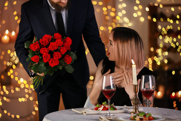 レストランでロマンチックな日付の間に彼のガール フレンドに花をあげる男 - 写真・画像