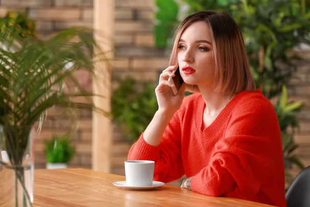 Jonge vrouw bellen met haar vriend in café - Foto, afbeelding