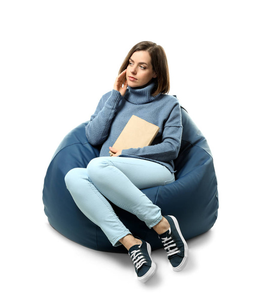 Young woman with book sitting on beanbag chair against white background - Photo, Image