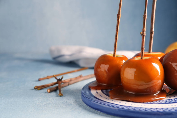 Delicious caramel apples with tree branches on plate - Photo, Image