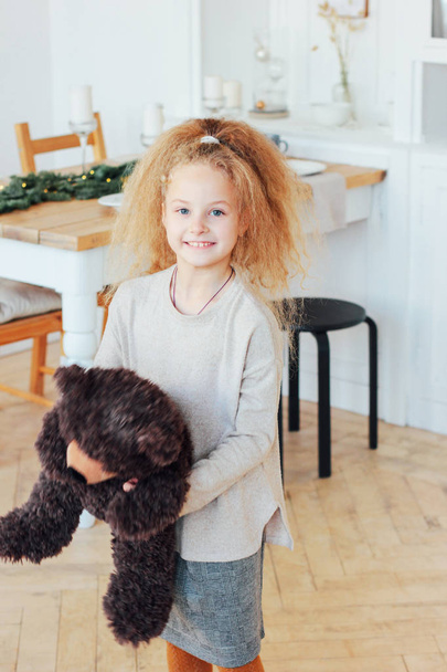 Hermosa niña de 8 años con juguete de oso en la sala de decoración de Navidad
 - Foto, imagen
