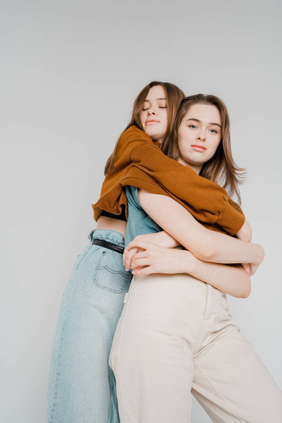 Deux sœurs jumelles belles filles hipsters en vêtements décontractés sur fond gris isolé, concept amour, amitié, âmes sœurs
 - Photo, image