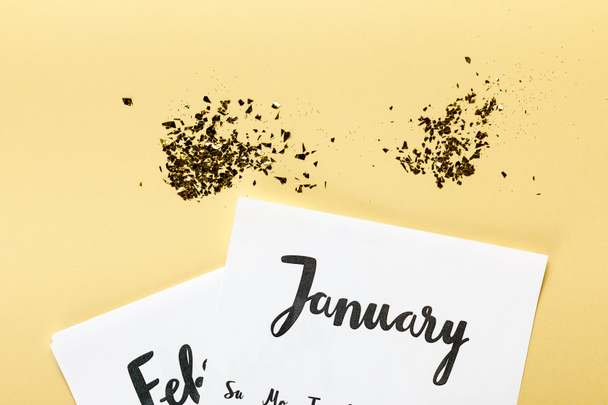 golden confetti with january and february calendar on beige background   - Photo, Image