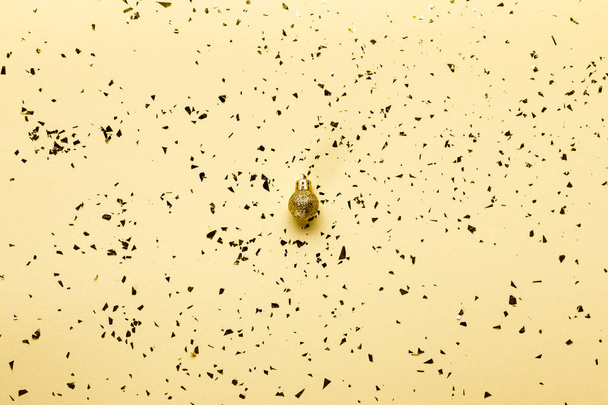 golden festive confetti and shiny christmas ball on beige background   - Photo, Image