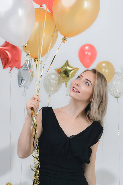 Beautiful young caucasian woman in black dress, happy smiling holding colorful balloons at fun party, studio portrait shot  white background. - Фото, зображення