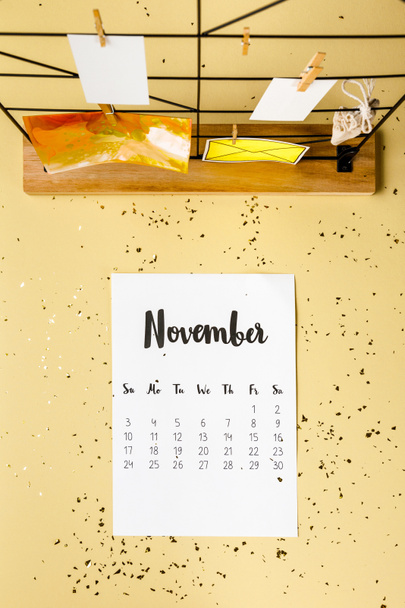 top view of november calendar with golden confetti and cards with clothespins on beige - Fotografie, Obrázek