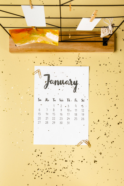 top view of january calendar with golden confetti and cards with clothespins on beige - Photo, Image