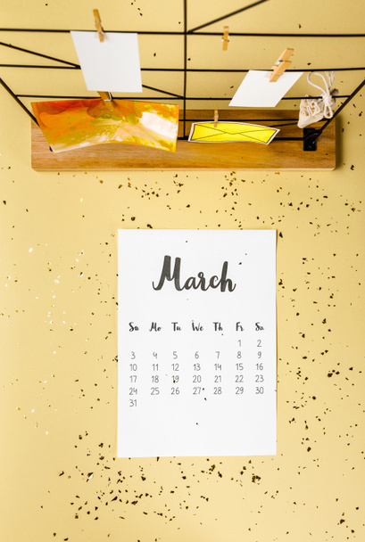 top view of march calendar with golden confetti and cards with clothespins on beige - Fotó, kép