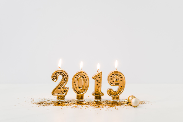 close-up view of burning 2019 candles and golden confetti on white background  - Foto, immagini