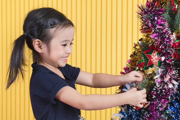 Petite fille asiatique mignonne docorating et jouer avec l'arbre de Noël avec bonheur. Concept pour célébrer au festival de Noël. - Photo, image