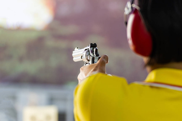 Mann hält Waffe zum Schießen bereit (selektiver Fokus auf den hinteren Teil der Waffe)) - Foto, Bild