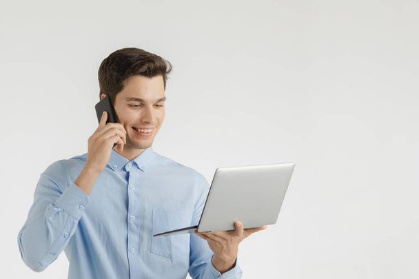 Молодой хипстер бизнесмен, уверенный в себе уравновешенный взгляд в компьютер в то время как ручка мобильного телефона, портрет изолирован на белом фоне
. - Фото, изображение