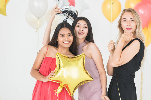 La diversidad de las mujeres felices jóvenes se divierten juntas en la fiesta, fondo blanco y globos festivos coloridos
. - Foto, imagen