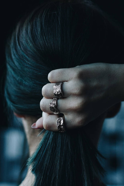 Back view of young woman with tail and silver rings on hand - Foto, immagini