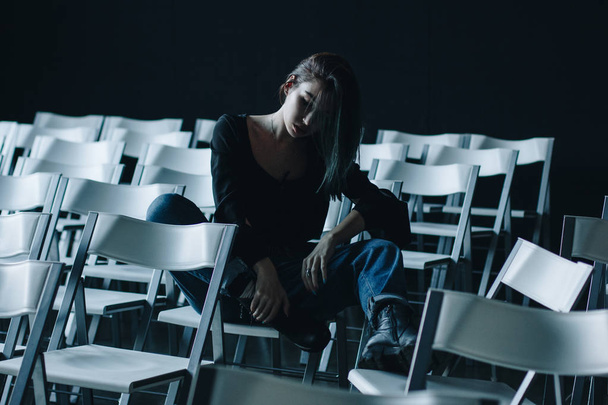 Young woman in black blouse and blue jeans in empty conference hall - Photo, Image