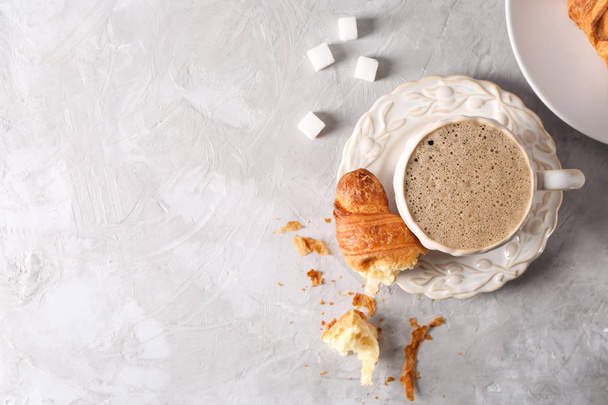 Tasse leckeren aromatischen Kaffee mit Croissant auf hellem Tisch - Foto, Bild