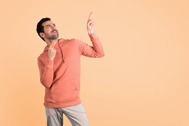 Человек в розовой толстовке, указывая указательным пальцем отличная идея и глядя вверх на охер фон
 - Фото, изображение