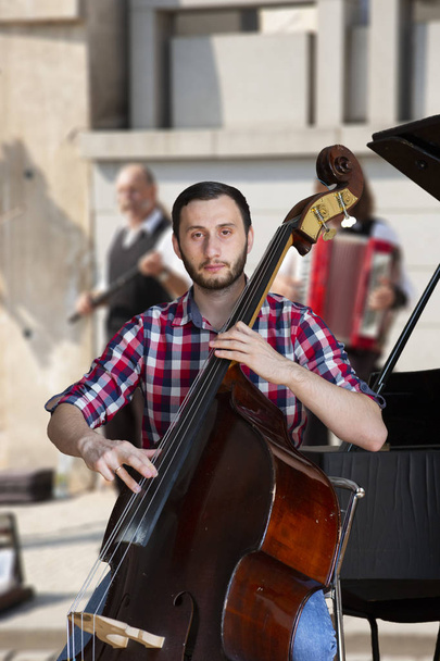 Double bass player playing contrabass Image on the background of the city Portrait - Foto, Bild