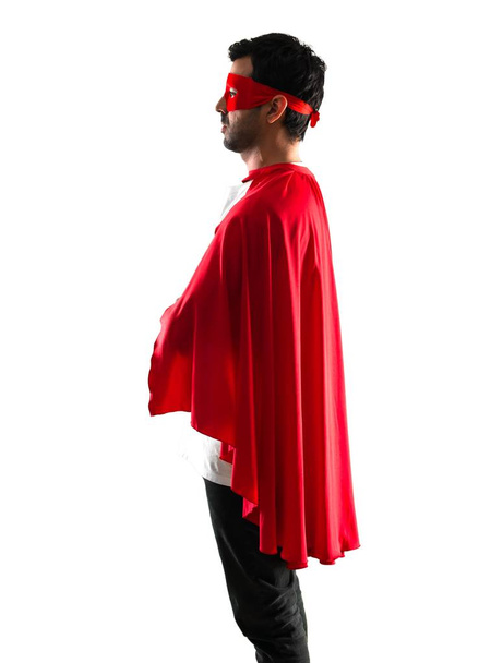 Υπερήρωα άνθρωπο με μάσκα και κόκκινη Μπέρτα σε πλάγια θέση σε απομονωμένες άσπρο φόντο - Φωτογραφία, εικόνα