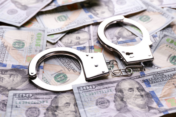 Dollar banknotes with handcuffs on table. Corruption concept - Photo, Image