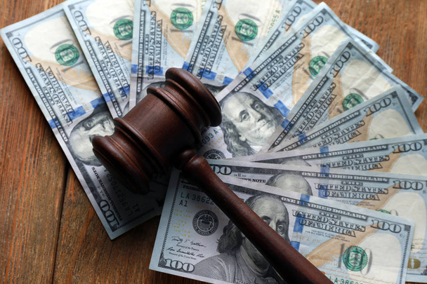 Judge's gavel with dollar banknotes on wooden table. Corruption concept - 写真・画像