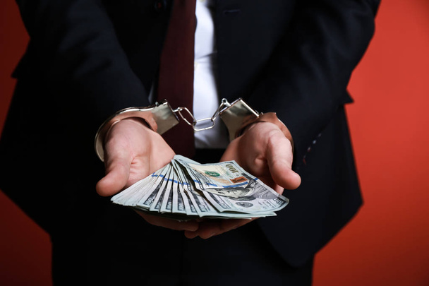 Businessman in handcuffs with bribe on color background, closeup. Corruption concept - Photo, Image