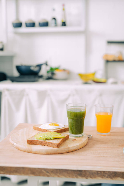 Healthy breakfast with fried egg, toasts and avocado with fresh juice on wooden table. - Valokuva, kuva