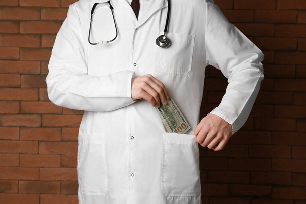 Lekarz wprowadzenie łapówkę w kieszeni w pobliżu mur z cegły. Koncepcja korupcja - Zdjęcie, obraz