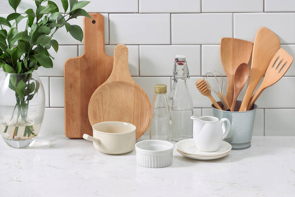 rustic kitchenware and ceramic jug with wooden cooking utensil set on white tile background - Valokuva, kuva