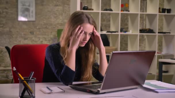 Portrait of blonde caucasian businesswoman working with laptop in office faces trouble and confusedly puts her hands on hand. - Filmati, video