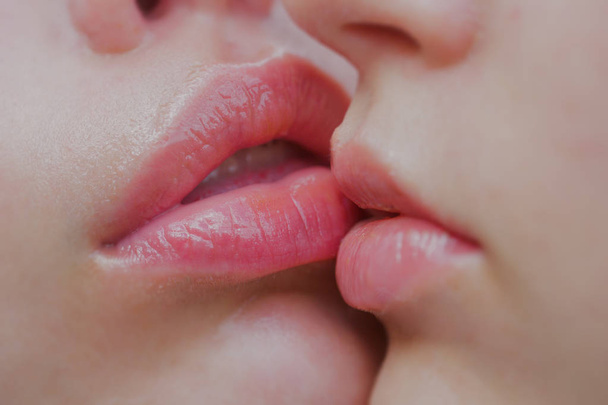 Λεσβιες ζευγάρι φιλί στα χείλη. Πάθος και αισθησιακό άγγιγμα. Δύο όμορφες σέξι λεσβίες στην αγάπη. Περιποίηση Χειλιών και ομορφιά. Closeup όμορφη νεαρή γυναίκα υγιή χείλη. Closeup των γυναικών στόματα φιλιά - Φωτογραφία, εικόνα
