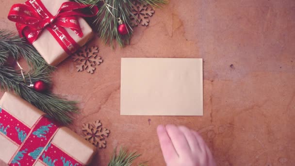 Mutlu Noel kavramı Çam ağaç dalları, hediye kutuları ve boş kartı masanın üzerine koyarak el ile - Video, Çekim
