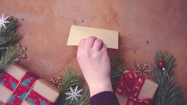 Mutlu Noel kavramı Çam ağaç dalları, hediye kutuları ve boş kartı masanın üzerine koyarak el ile - Video, Çekim