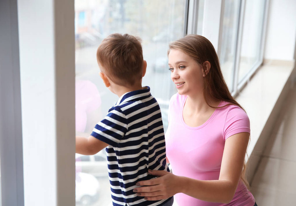 Young pregnant woman with her cute little son near window - Photo, Image