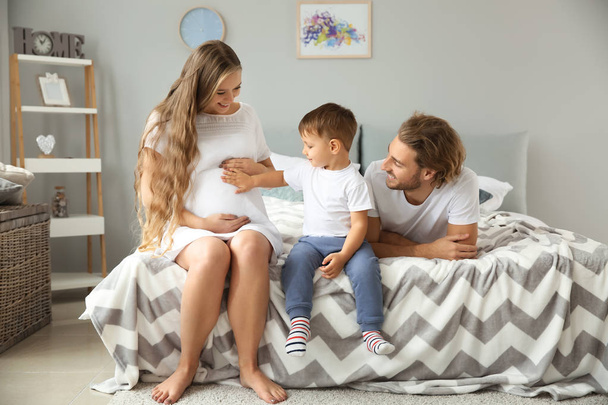 Giovane donna incinta con la sua famiglia in camera da letto
 - Foto, immagini