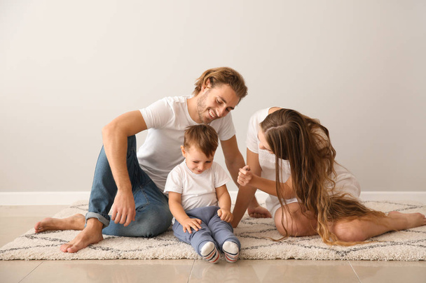 Πορτρέτο του ευτυχισμένη οικογένεια στο χαλί κοντά σε λευκό τοίχο - Φωτογραφία, εικόνα
