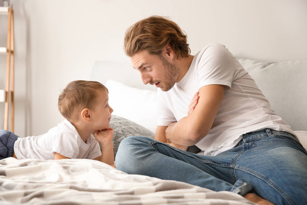 Otec a jeho roztomilý malý syn na posteli doma - Fotografie, Obrázek