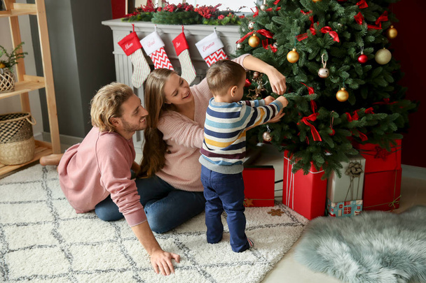 Happy family decorating Christmas tree at home - Foto, Imagen