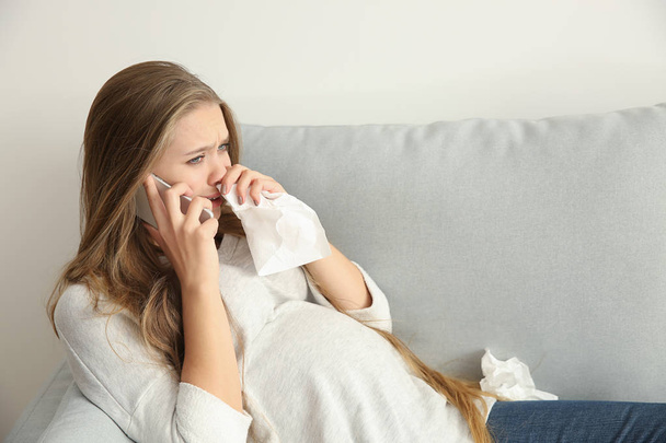 Nuori raskaana oleva nainen puhuu puhelimitse ja itkee mielialan muutoksen vuoksi
 - Valokuva, kuva
