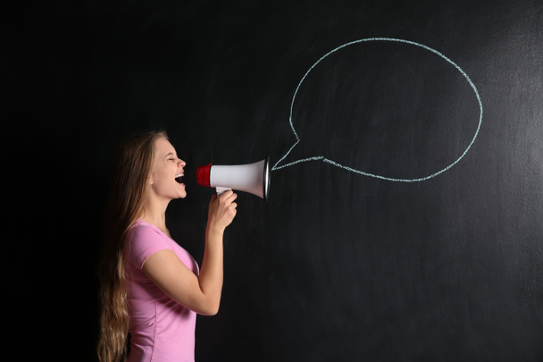 Gritando jovem mulher com megafone perto de bolha de fala desenhada no fundo escuro
 - Foto, Imagem