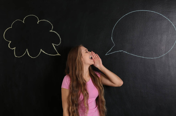 Screaming young woman near blank speech bubbles drawn on blackboard - Photo, Image