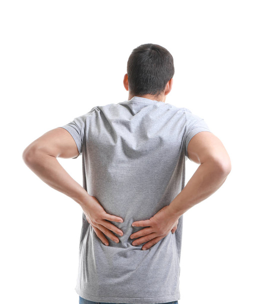 Young man suffering from back pain on white background - 写真・画像