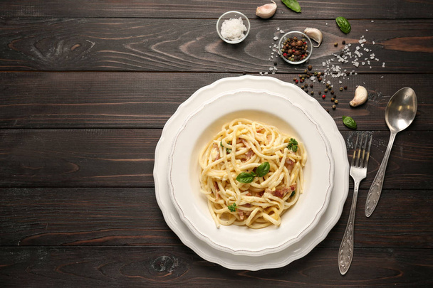 Teller mit leckeren Pasta Carbonara auf dunklem Holztisch - Foto, Bild