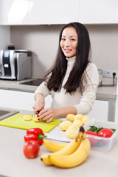 Photo of young brunette cutting vegetables in kitchen - Foto, Imagem